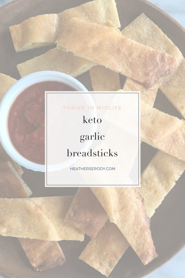 keto garlic breadsticks recipe: Just 3 carbs per 3 breadsticks! This recipe is the result of trying to make my keto bagel dough into keto crackers. The result wasn't crackers at all, but delicious breadsticks! I just spread out the dough like a rectangular pizza crust on a parchment-lined baking sheet, & sprinkled it with garlic powder. After it comes out of the oven just let it cool for a few minutes and then cut it into breadsticks with a pizza cutter. | Thrive In Midlife #keto #ketogenic #ketorecipes #lchf